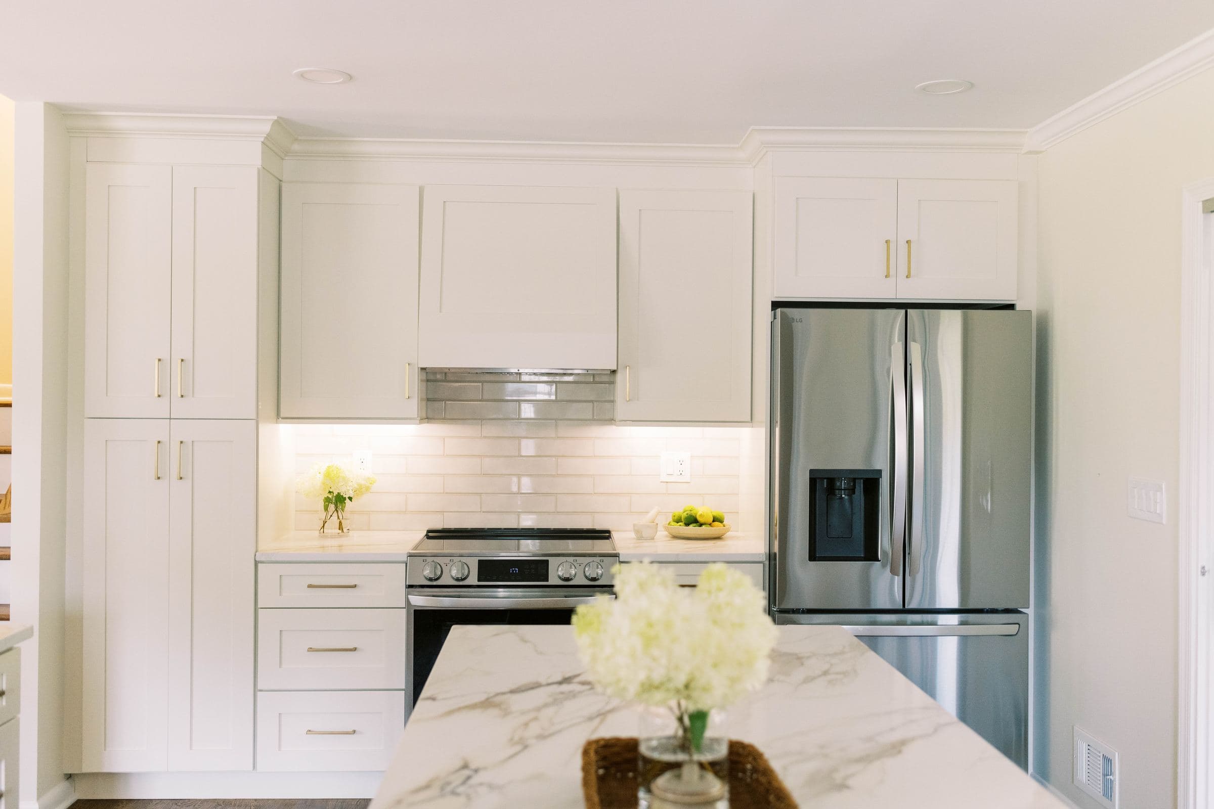White shaker kitchen with a marble-look island and stainless appliances