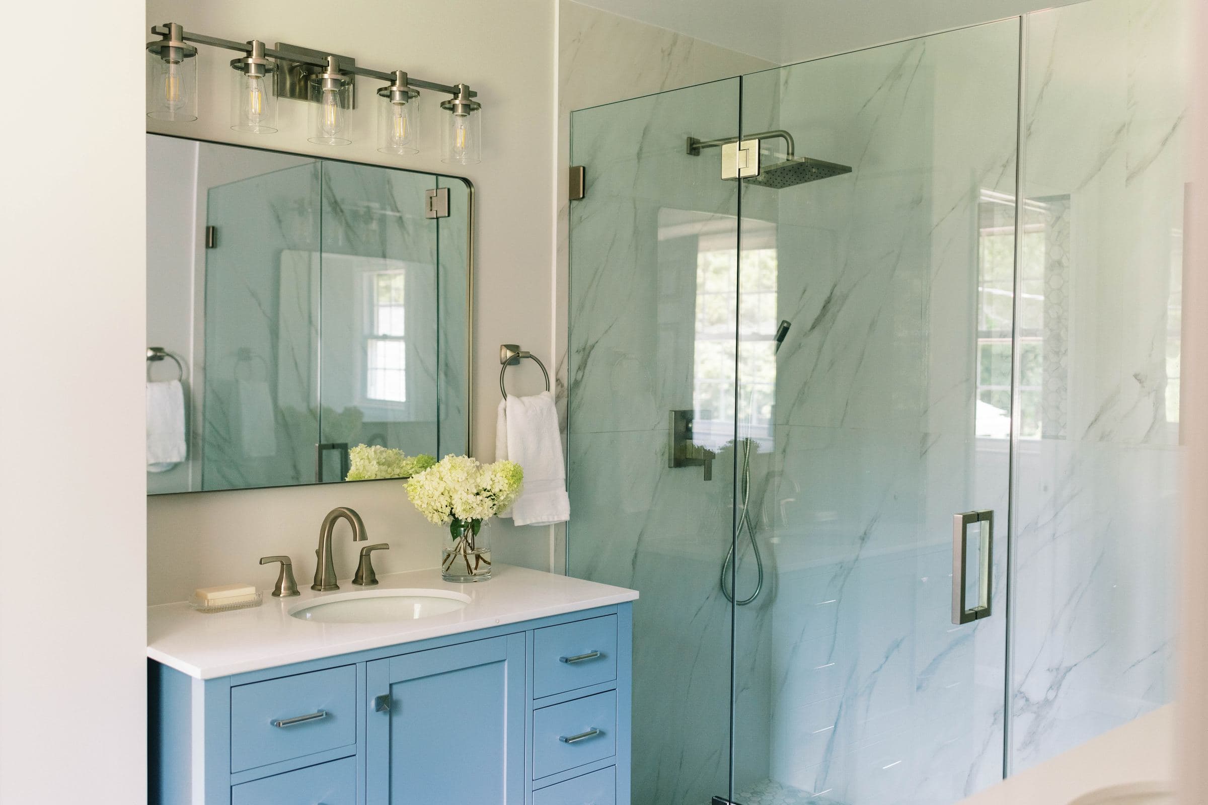 Bathroom with a blue vanity and a frameless glass walk-in shower